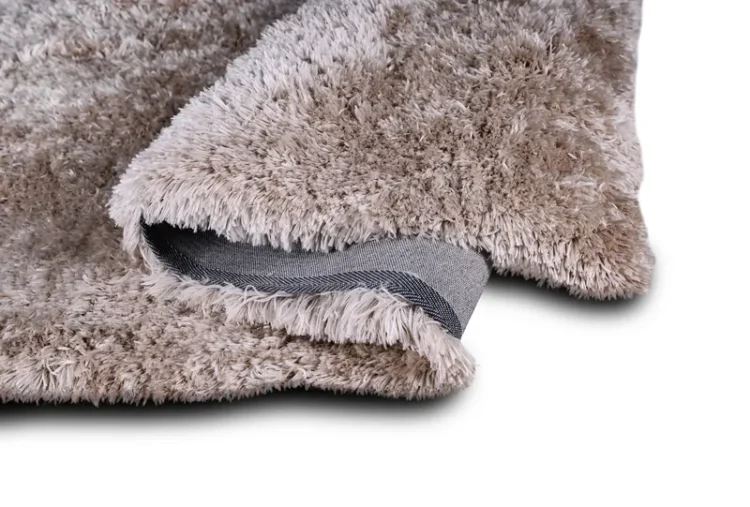 A fluffy beige rug with a soft, plush texture. The rug is folded at one corner, revealing the underside