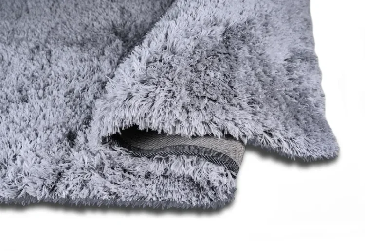 A thick, fluffy silver rug that is folded at one corner