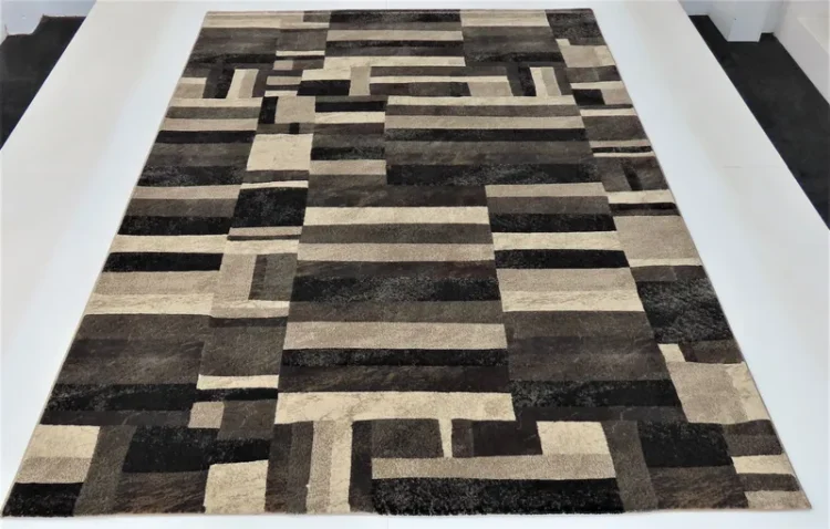 A rug with a geometric pattern made up of rectangles and squares in various shades of brown, black, and cream