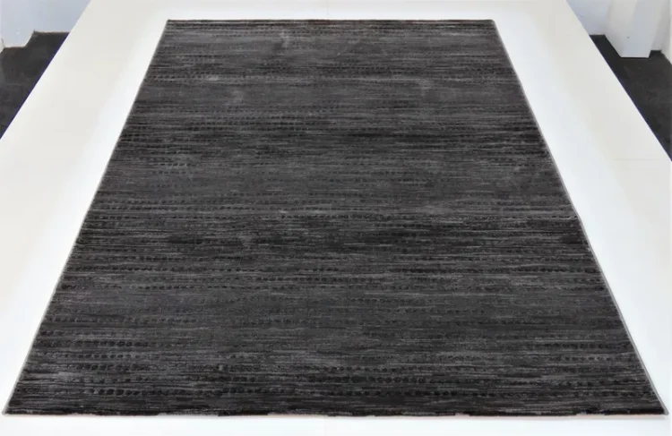 A dark grey rug with a subtle striped pattern running horizontally. It has a soft, plush texture