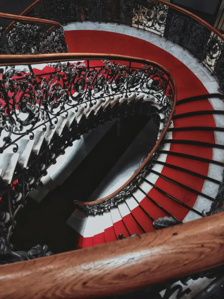 long white spiral staircase with a red runner in the centre