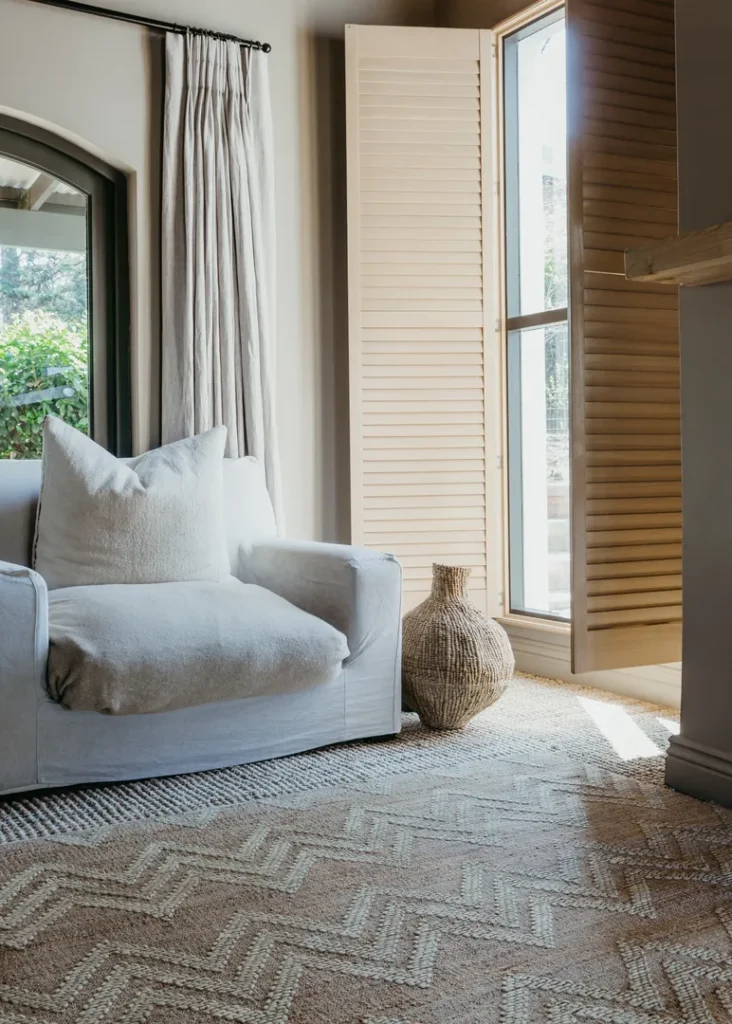 A white chair in a room with natural looking chevron rug