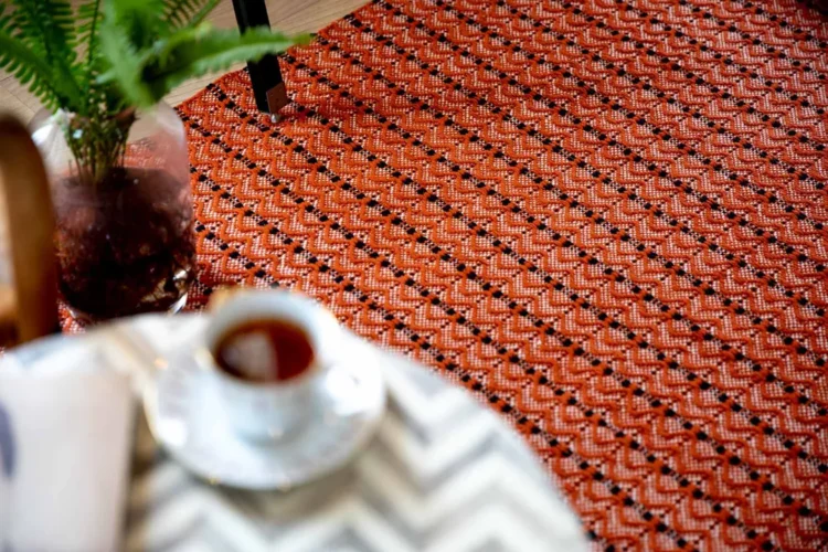 a cup of tea on a table sitting atop Dune Orange Rug