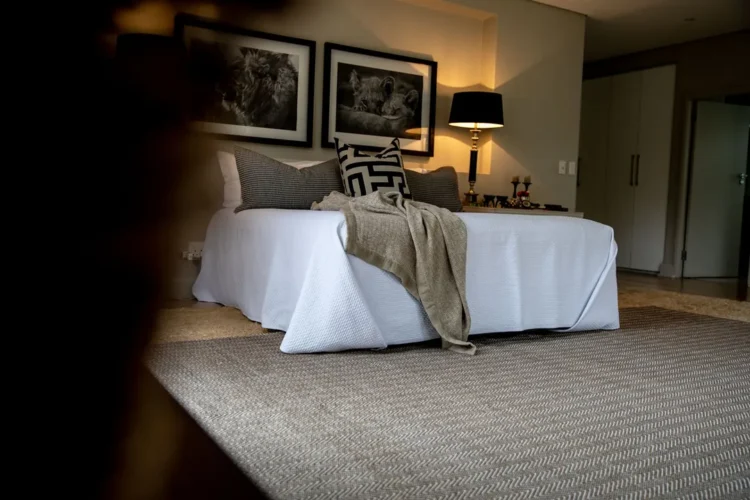 a bed with pillows and a lamp on a kalahari rug