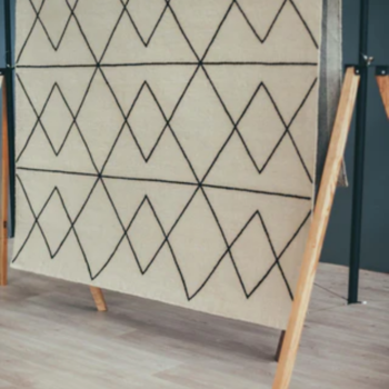 white peak rug with thin solid black line hanging on a frame