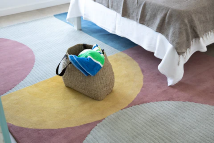 bed and woven bag on colourful sunset rug